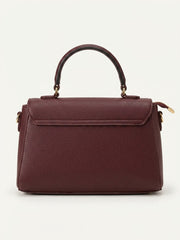 Back view of burgundy top handle flap bag with detachable strap