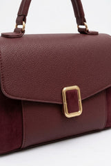 Close-up of burgundy bag showing gold buckle and suede texture