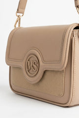 Close-up of tan flap bag showing monogram medallion and woven panel