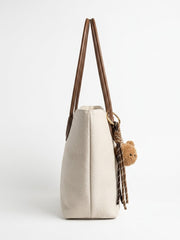 Side profile of cream slouch tote showing bear charm
