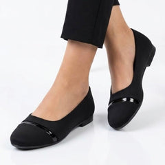 Black patent cap toe ballet flats worn with black trousers