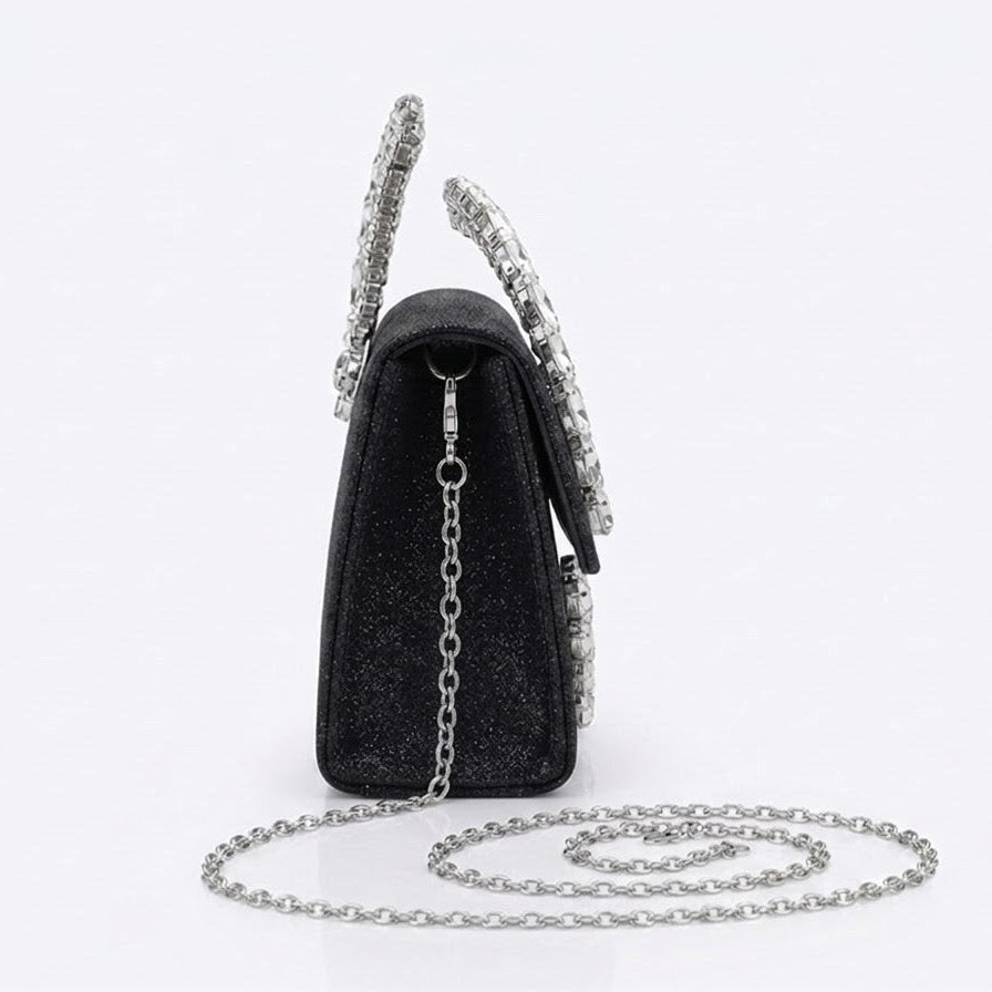 Side view of black crystal handle clutch with chain strap coiled