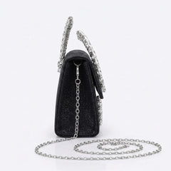 Side view of black crystal handle clutch with chain strap coiled