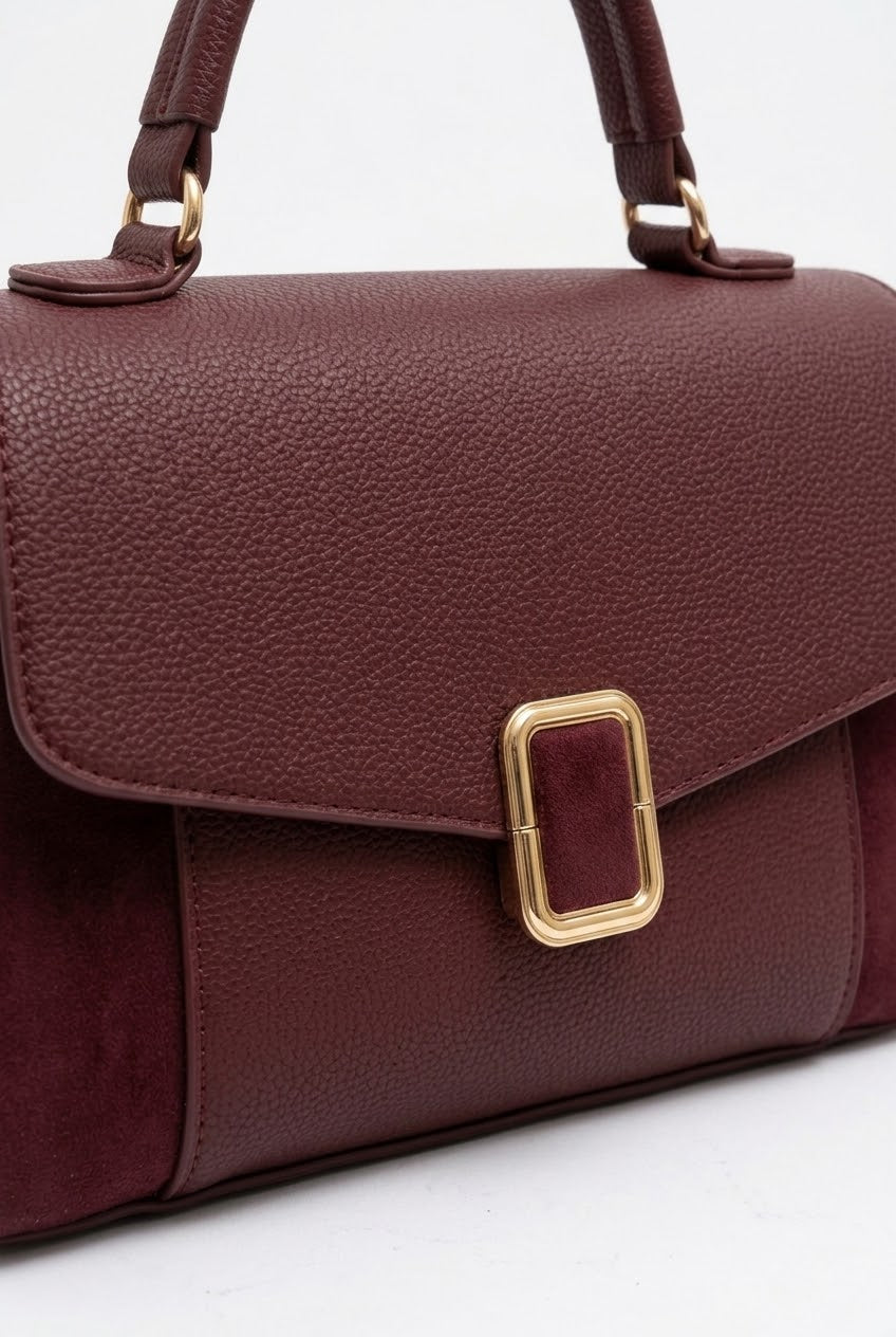 Close-up of burgundy bag showing gold buckle and suede texture