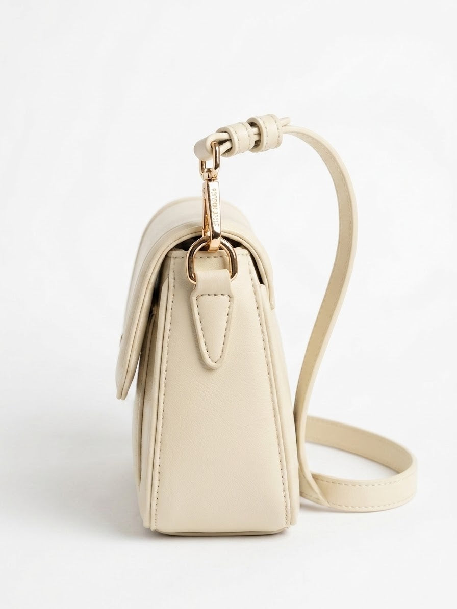 Side profile of cream flap shoulder bag with strap