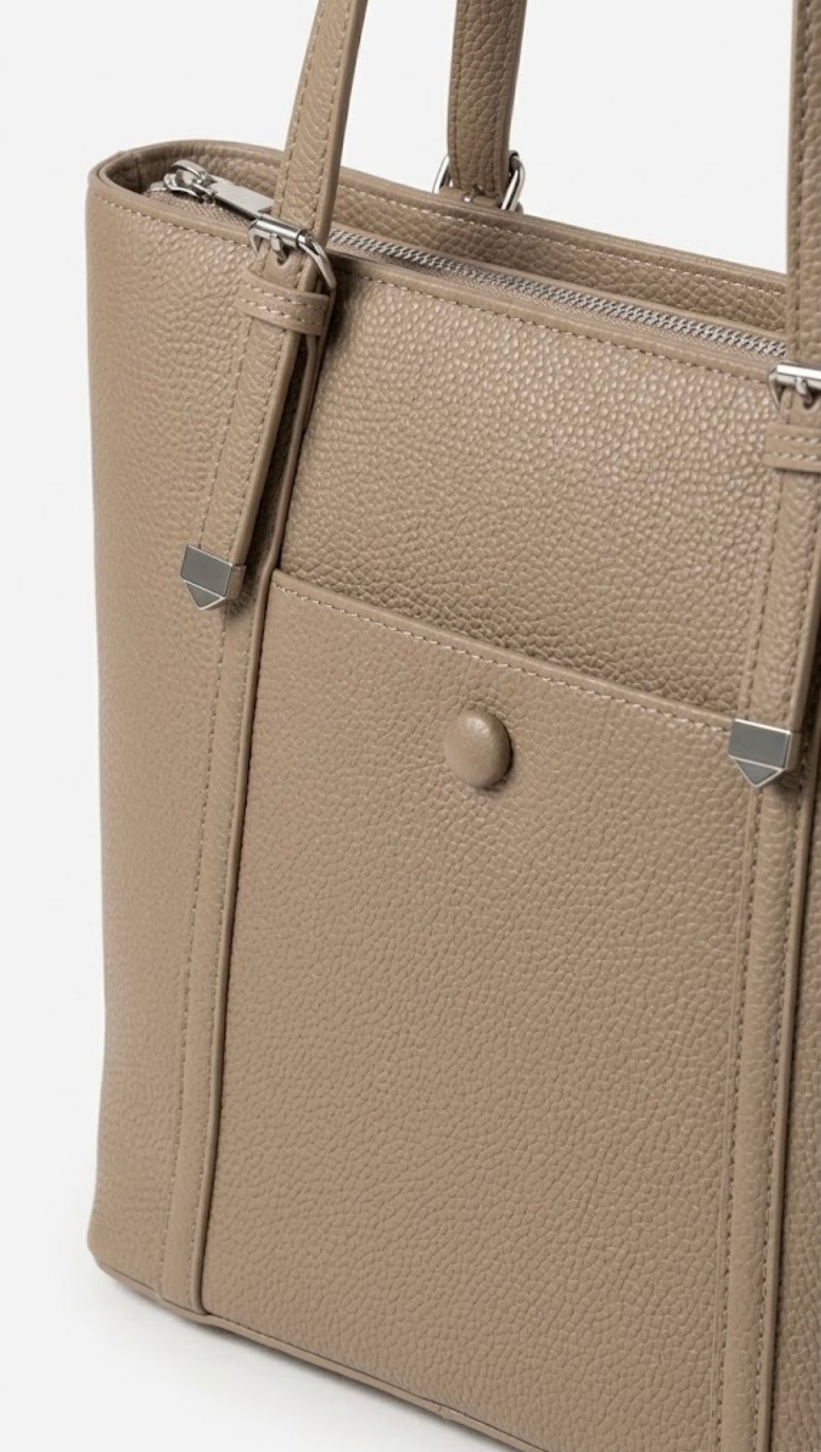 Close-up of taupe tote showing corner caps and stud detail