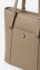Close-up of taupe tote showing corner caps and stud detail