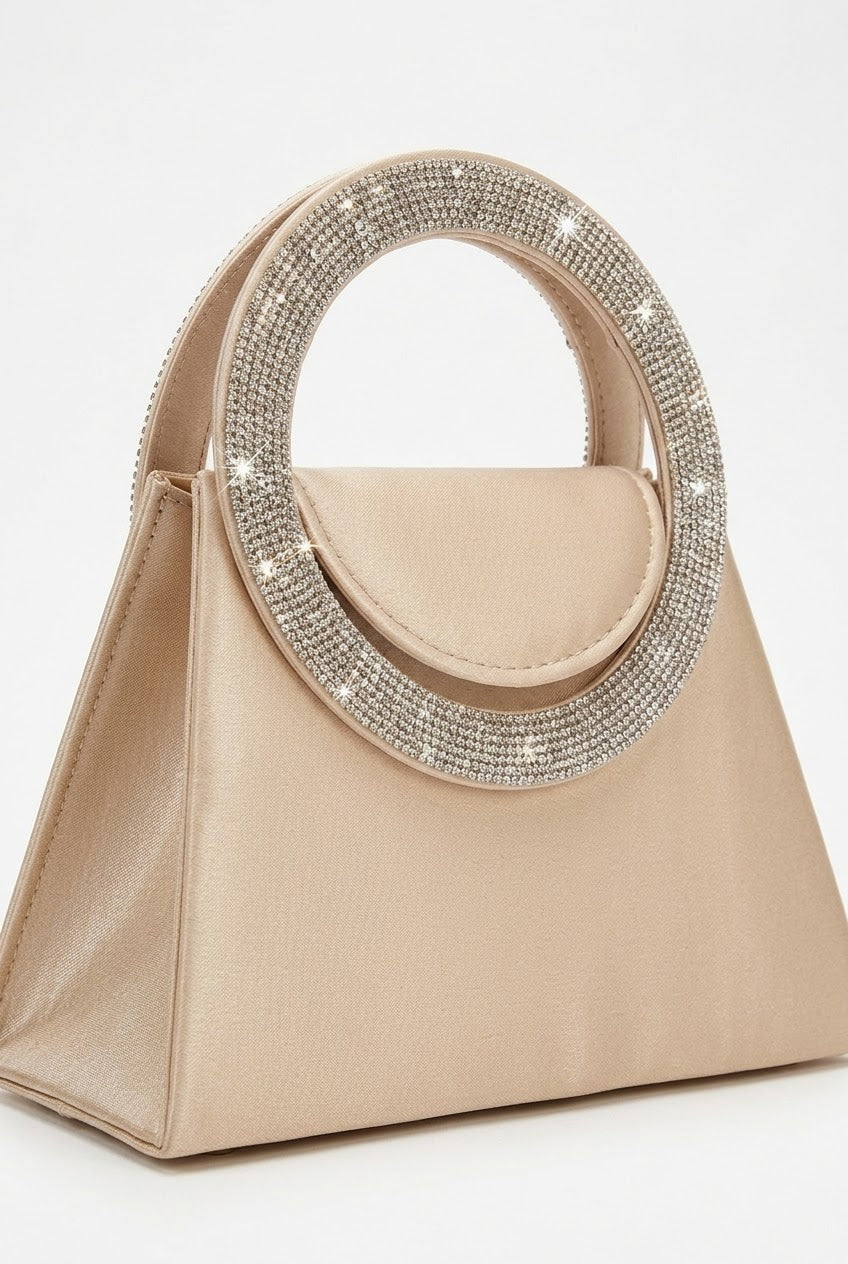 Angled view of nude trapeze bag showing crystal handle and flap