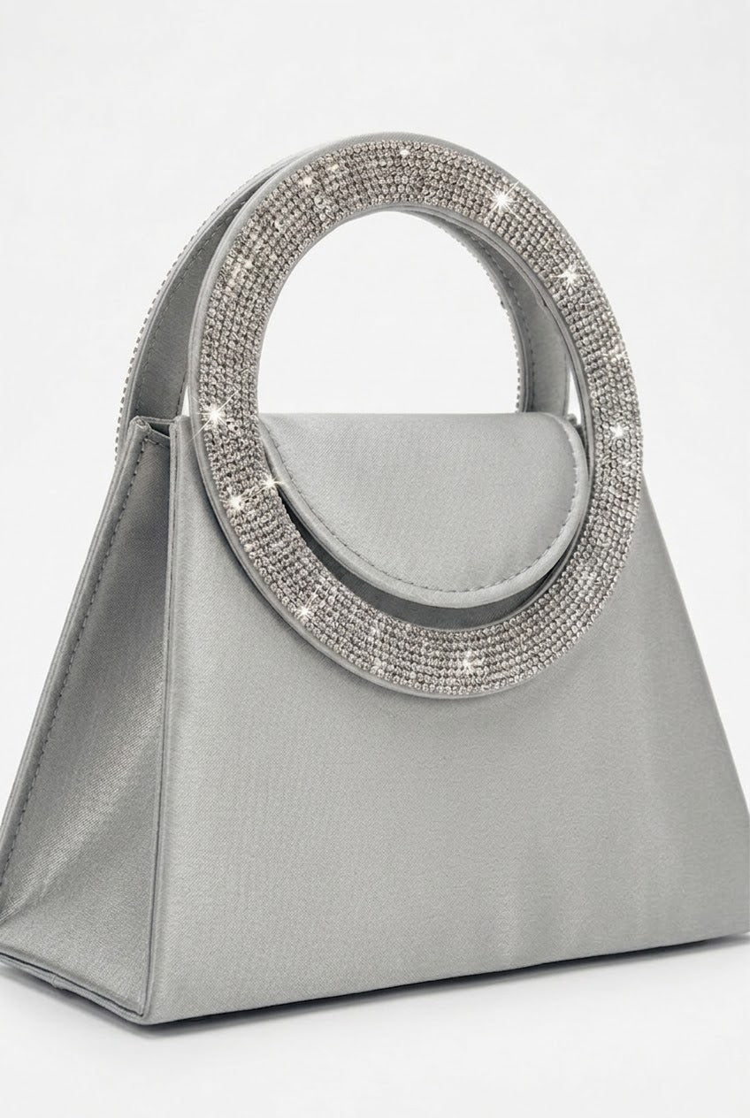 Angled view of silver trapeze bag showing crystal handle