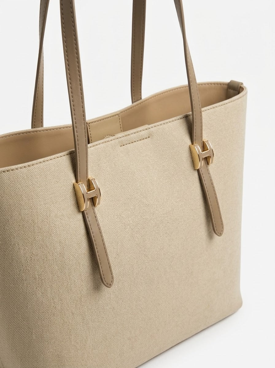Angled view of beige shopper tote showing buckle hardware