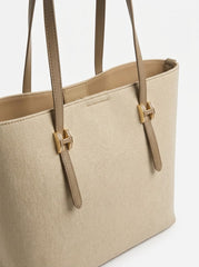 Angled view of beige shopper tote showing buckle hardware