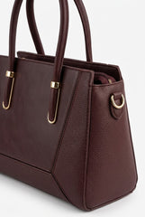 Close-up of burgundy satchel showing panel seams and gold hardware