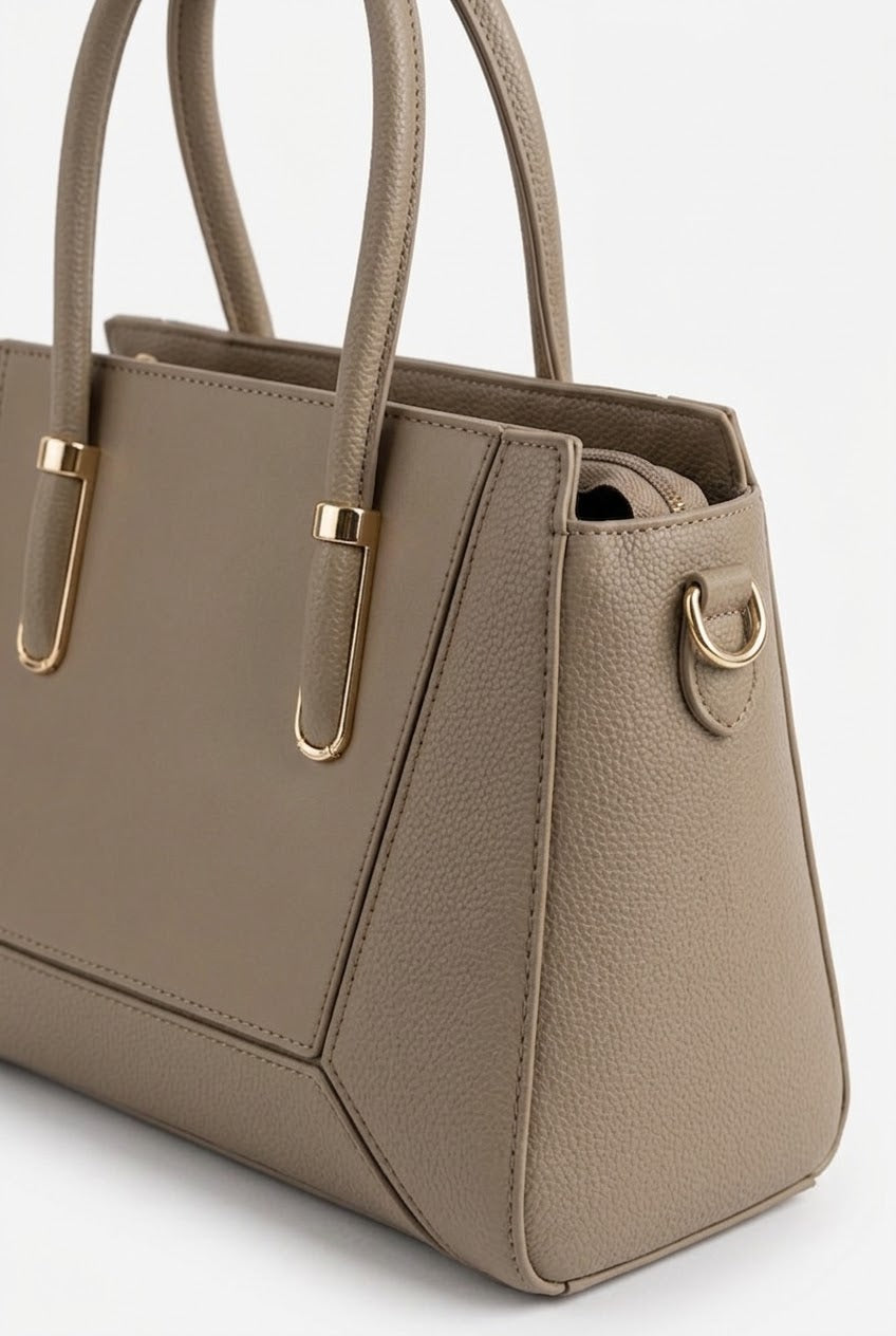 Close-up of taupe satchel showing panel seams and gold hardware