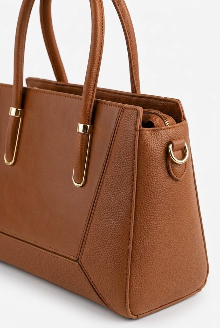 Close-up of tan satchel showing panel seams and gold hardware