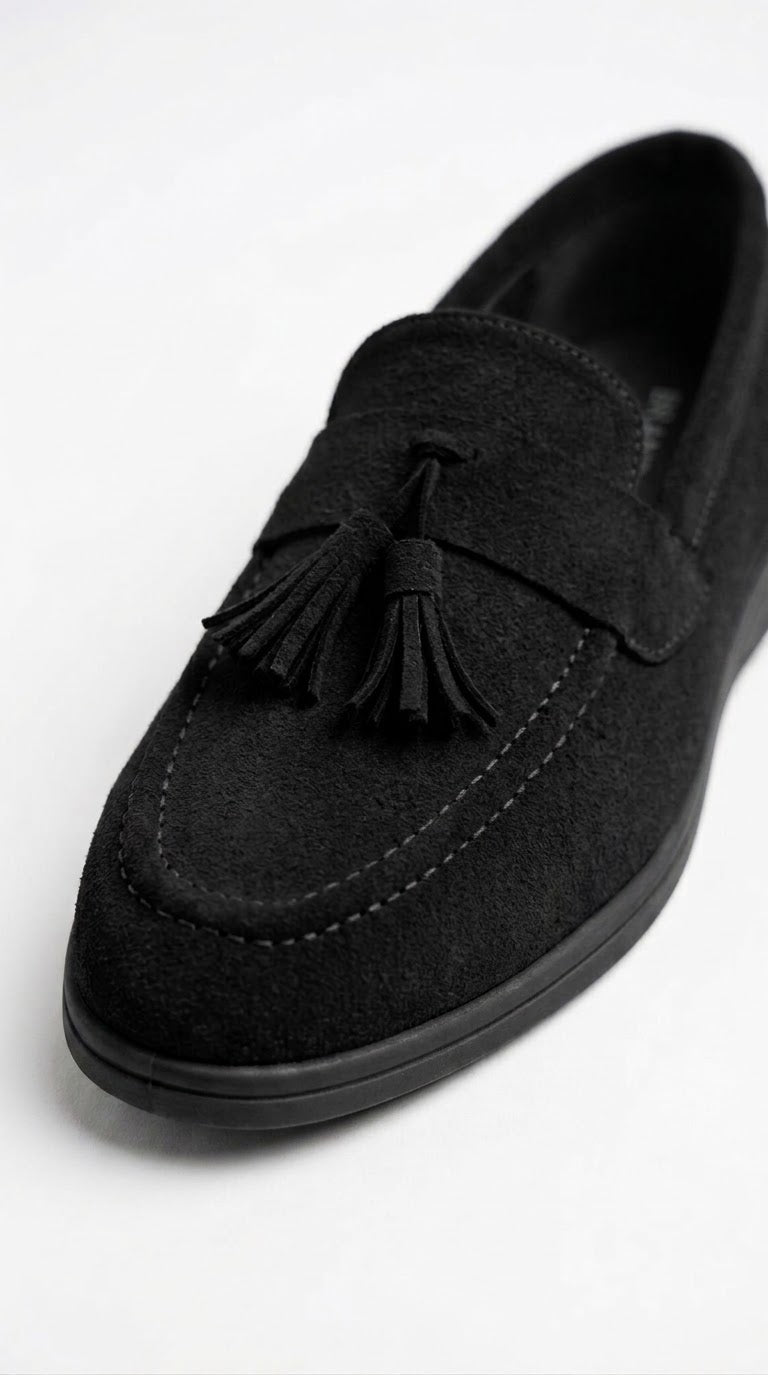 Close-up of black suede loafer showing tassel detail
