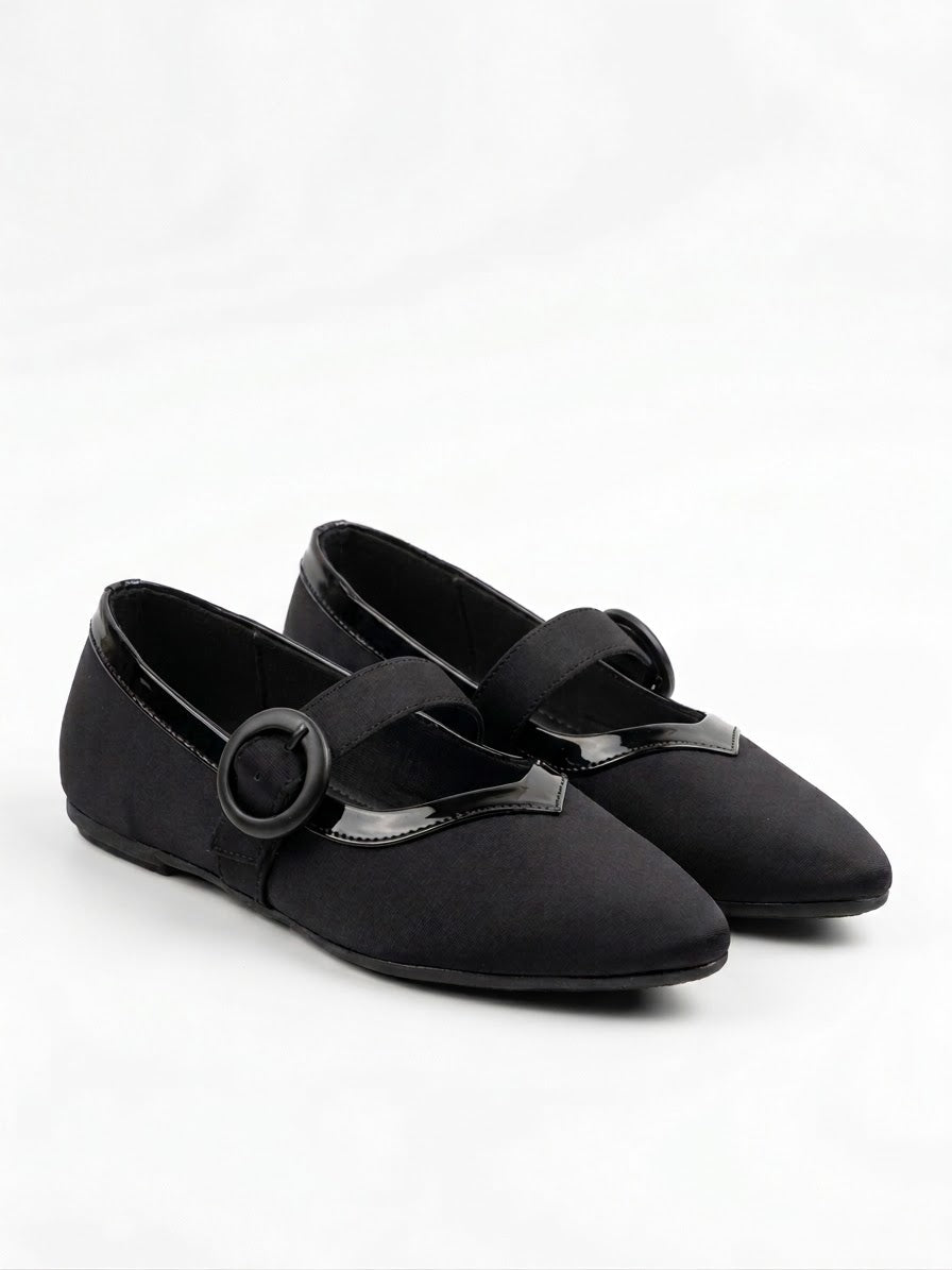 Pair of black Mary Jane flats with round buckle straps, angled view