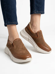 Tan slip-on sneakers worn with blue jeans