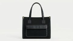 Black canvas tote shown straight on with leather trim detail